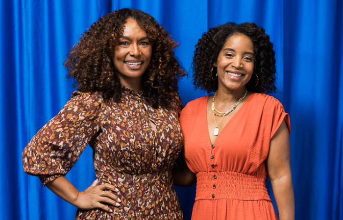 A photo of Janet Mock standing with Angela Poe Russell in front of a blue background.
